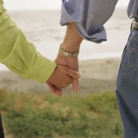 detail-of-senior-couple-holding-hands-at-beach-bxp155468